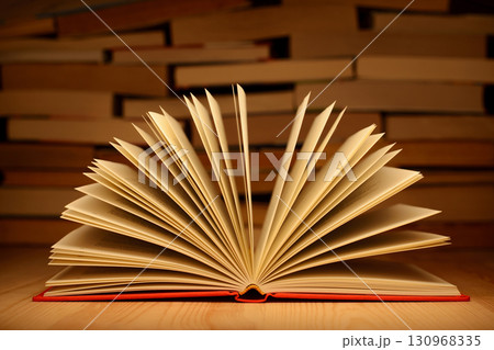 Open book on wooden table with a wall of books at the background. Concept of education, studying, knowledge 130968335