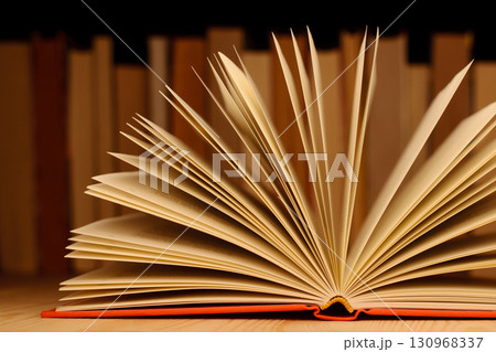 Close up picture of open book on wooden table in front of row of books. Concept of reading books, education, information 130968337