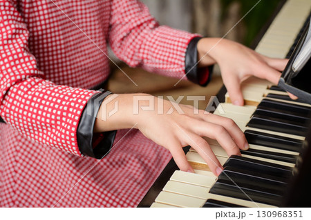 Smart little girl playing the piano at home. Small child learning to play the piano at home, getting ready to the classes in music school 130968351