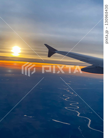 A picture from an airplane of a sunset. View from the window with the wing visible 130968430