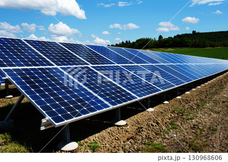 a row of solar panels sitting on top of a lush green field next to a mountain 130968606