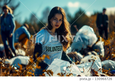 female volunteer looking at a camera picking up a plastic litter . 130968726
