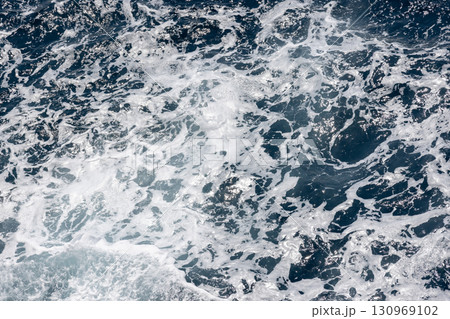 Dynamic ocean waves creating intricate white foam patterns on the surface Dynamic ocean waves creating intricate white foam patterns on the surface 130969102