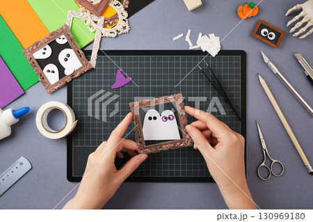 Making a Halloween craft. Hands place the frame on the craft. Making a Halloween craft. Hands place the frame on the craft. 130969180