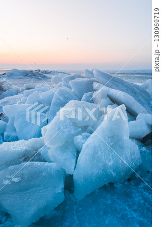 Ice slabs on a frozen coastline at sunset, glowing with evening light and deep blue shadows. Ice slabs on a frozen coastline at sunset, glowing with evening light and deep blue shadows. 130969719