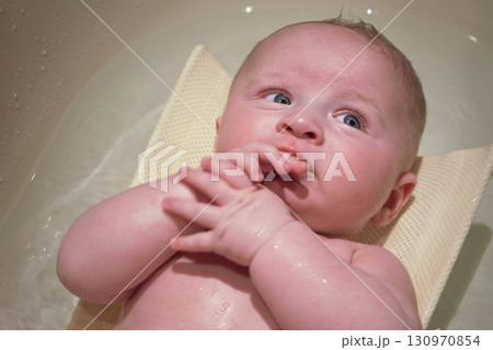 Infant baby boy washed in small bath tub, view from above Infant baby boy washed in small bath tub, view from above 130970854