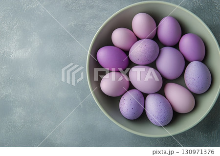 Decorative Purple Eggs Arranged in a Bowl on a Grey Background. 130971376