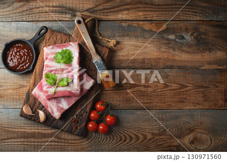 Raw pork ribs with spices, salt and rosemary on dark wooden background 130971560
