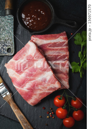 Raw meat. Raw pork ribs from the back with meat on a black background. background image 130971570