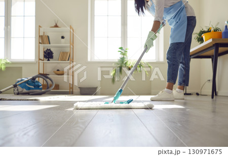 Young cleaner or housewife doing housework and mopping the floor in the living room 130971675
