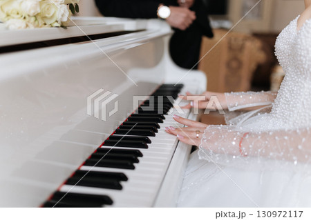 Bride playing piano in pearl wedding dress, elegant romantic wedding atmosphere 130972117