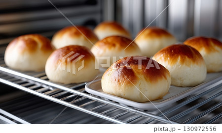 Freshly baked bread rolls cooling on a wire rack in a kitchen 130972556