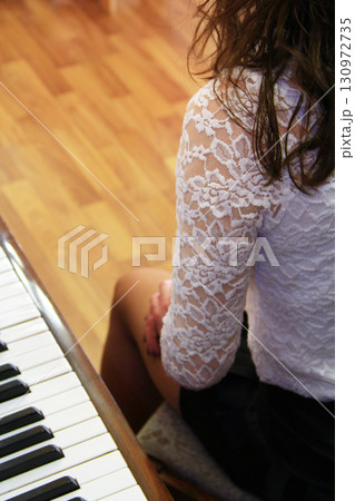 Piano keys and legs of pianist girl. Piano are ready to play. Keyboard musical instrument 130972735