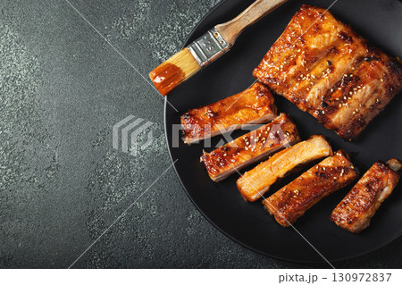 Hot grilled spare ribs from a summer BBQ served on a plate with sauce. Top view. Copy space Hot grilled spare ribs from a summer BBQ served on a plate with sauce. Top view. Copy space 130972837