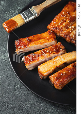 Hot grilled spare ribs from a summer BBQ served on a plate with sauce. Top view. Copy space Hot grilled spare ribs from a summer BBQ served on a plate with sauce. Top view. Copy space 130972838