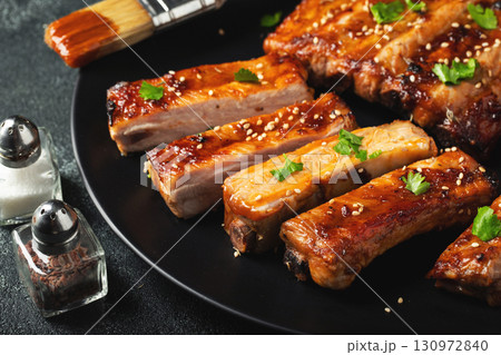 Hot grilled spare ribs from a summer BBQ served on a plate with sauce. Top view. Copy space Hot grilled spare ribs from a summer BBQ served on a plate with sauce. Top view. Copy space 130972840