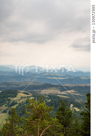 Extensive view of green forested mountains and valleys under gloomy cloudy sky  130972995