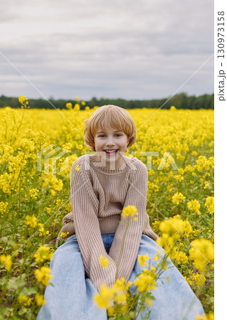 Girl sitting in yellow rapeseed field front view with copy space Girl sitting in yellow rapeseed field front view with copy space 130973158