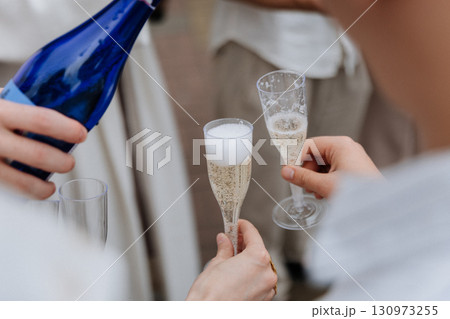 Pouring sparkling wine into plastic flutes during outdoor celebration toast Pouring sparkling wine into plastic flutes during outdoor celebration toast 130973255