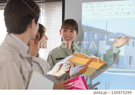 スクリーンの前で宅地開発の打ち合わせをする3人の男女 130973294