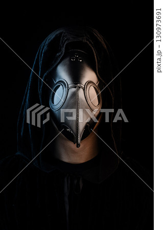 Plague doctor with crow-like mask on black background. Creepy mask for Halloween, historical costume Plague doctor with crow-like mask on black background. Creepy mask for Halloween, historical costume 130973691