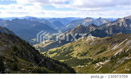 Scenic mountain range with a deep valley and winding hiking trails. Panoramic aerial view of an alpine landscape in the summer. 130973709