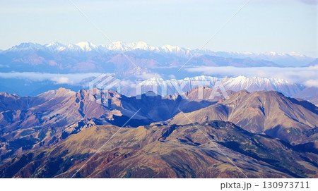 Scenic aerial view of layered mountain landscape and ranges. Vast alpine wilderness with snow covered mountains in the distance. 130973711