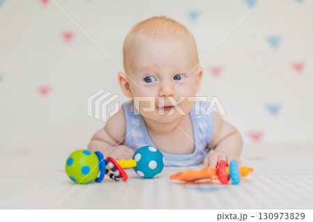 Adorable baby playing with colorful rattles on a soft baby play mat at home. Concept of early development, sensory play, and safe learning environment for infants Adorable baby playing with colorful rattles on a soft baby play mat at home. Concept of early development, sensory play, and safe learning environment for infants 130973829