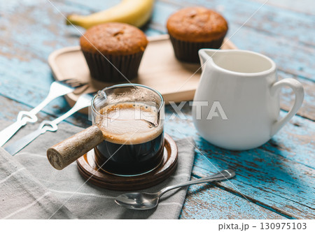 A cup of hot black coffee, Espresso, fresh baked muffins. Banana cupcake close-up as dessert for coffee break. Top view. refreshing morning and day A cup of hot black coffee, Espresso, fresh baked muffins. Banana cupcake close-up as dessert for coffee break. Top view. refreshing morning and day 130975103