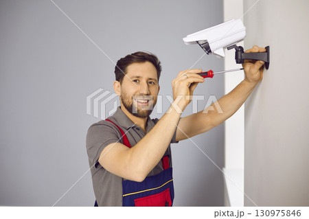 Technician man in uniform installing CCTV camera on wall Technician man in uniform installing CCTV camera on wall 130975846