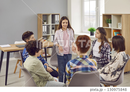 Group of school boys and girls having a discussion about something in the classroom Group of school boys and girls having a discussion about something in the classroom 130975848