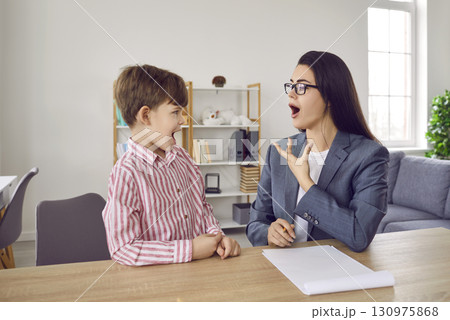 Professional young woman speech therapist training with a little boy patient at her office. Professional young woman speech therapist training with a little boy patient at her office. 130975868