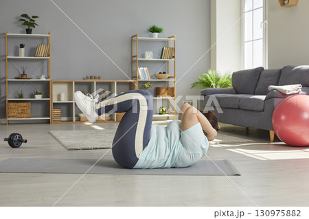 Fat funny woman shaking press and doing sport exercises lying on the floor at home. Fat funny woman shaking press and doing sport exercises lying on the floor at home. 130975882