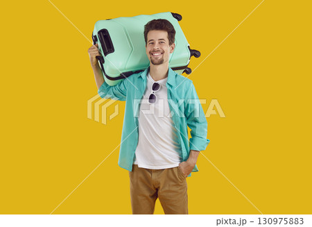 Portrait of happy young man with suitcase who is going on vacation to warm country. 130975883