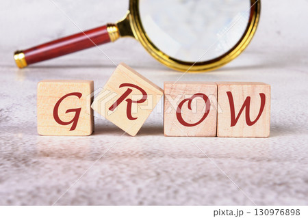 The concept word GROW is collected of wooden cubes with a magnifying glass in the background. Investment concept 130976898