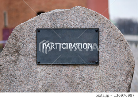 PARTICIPATION concept letters. Copy space. PARTICIPATION word written on the plaque of a large stone monument. 130976987
