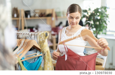 Adult woman choosing jumpsuit in clothing store 130978030