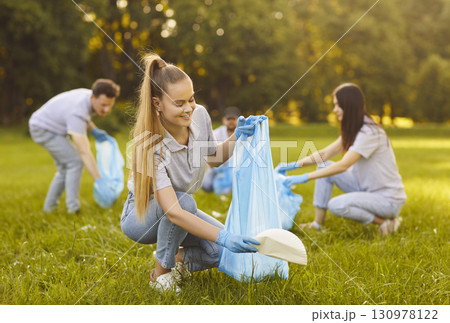 Group of happy volunteers participating in environmental clean up, working together in park Group of happy volunteers participating in environmental clean up, working together in park 130978122