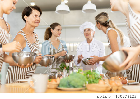 Mature woman holding bowl and talking to other members Mature woman holding bowl and talking to other members 130978123