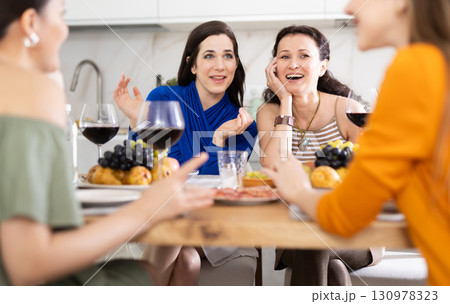 Four women are sitting at table, enjoying food and wine, chatting, talking, laughing. Four women are sitting at table, enjoying food and wine, chatting, talking, laughing. 130978323