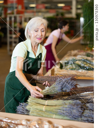 Elderly woman, hostess of the flower market, collects lavender in bouquet 130978360