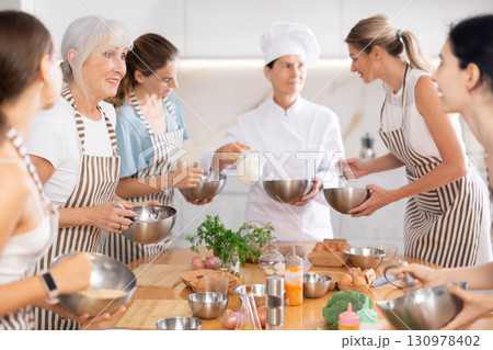 Mature woman holding bowl and talking to other members 130978402