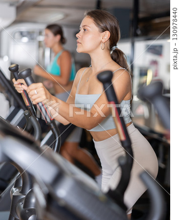 Young woman working out on elliptical machine 130978440