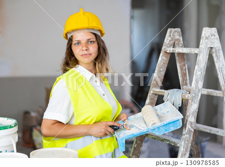 Woman builder holding paint roller and tray, home improvement works Woman builder holding paint roller and tray, home improvement works 130978585
