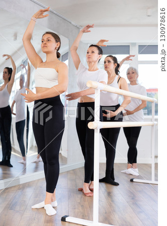 Group of women stand in position at ballet barre Group of women stand in position at ballet barre 130978616