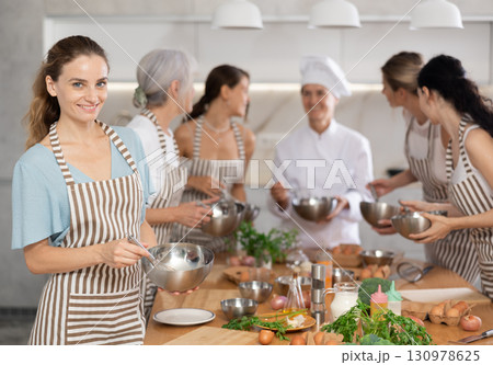 Girl while studying at culinary workshop, cooks appetizing sauce, marinade, dough in bowl. 130978625