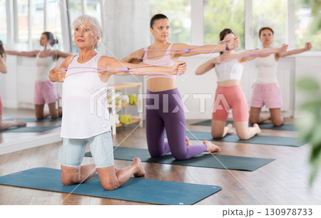 Senior lady doing xercises with figure eight resistance band in studio Senior lady doing xercises with figure eight resistance band in studio 130978733