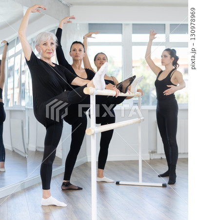 Students of dance studio perform exercises under supervision of middle-aged female coach. Students of dance studio perform exercises under supervision of middle-aged female coach. 130978969