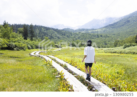 木道をハイキングする男性 130980255