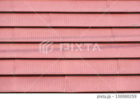 レンガ色の金属製の屋根のクローズアップ。金属の背景用テクスチャ素材 130980259